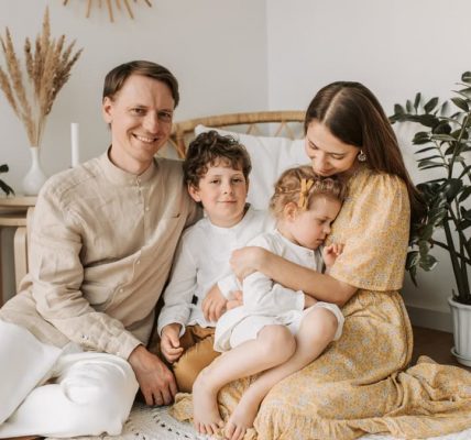 Happy family of four enjoying quality time together in a cozy, plant-filled room.