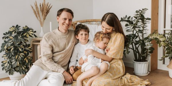 Happy family of four enjoying quality time together in a cozy, plant-filled room.